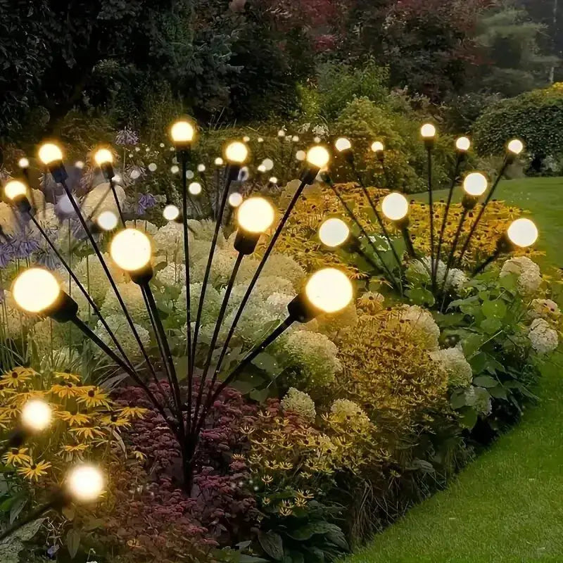 10-light solar lawn lamp set with wind-driven LED firefly bulbs on black metal stems along a flowering garden bed