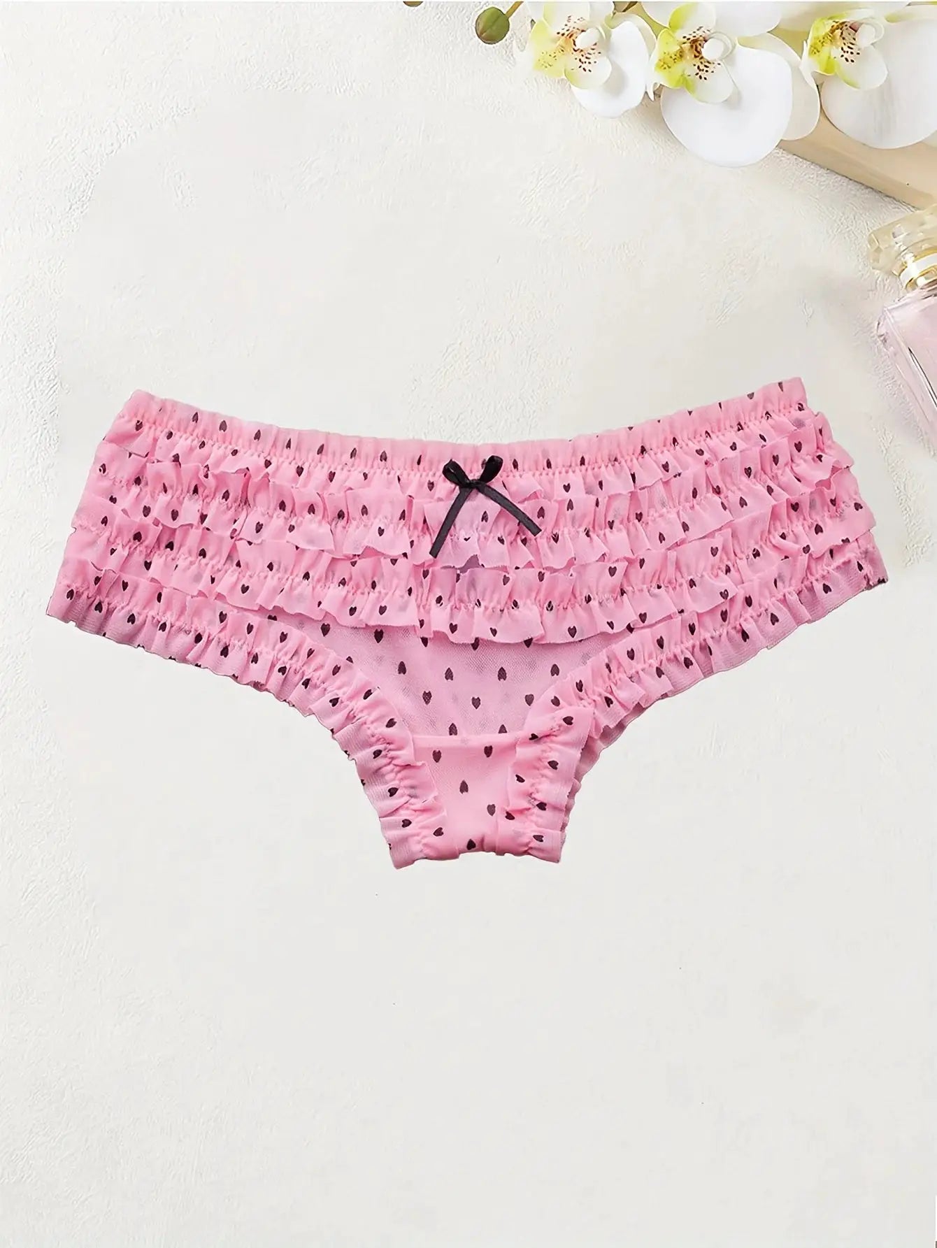 Pink women's low-rise brief with layered ruffles, small heart print and a black bow accent
