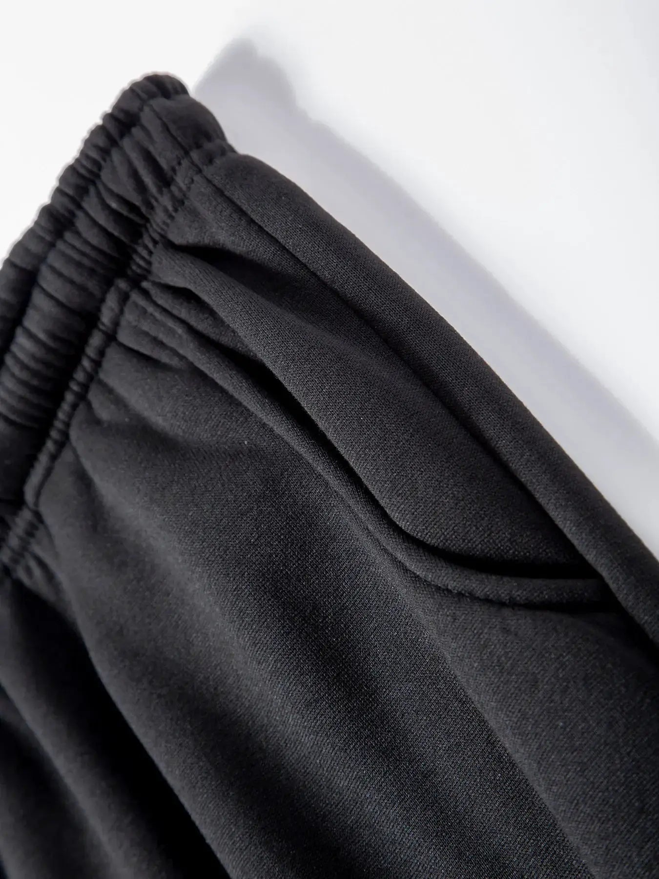 Men's black fleece jogger pants with elastic waistband – close-up fabric detail