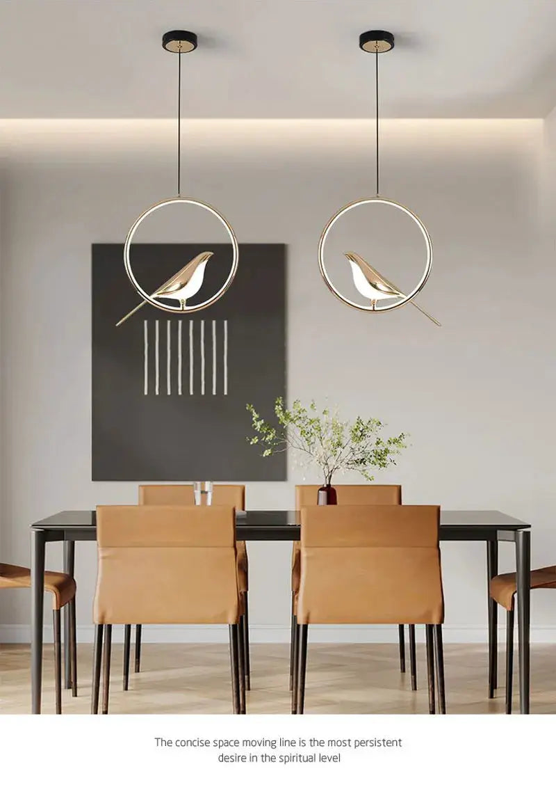 Rotatable magpie bird LED pendant lights, gold finish, pair hanging from ceiling over dining table
