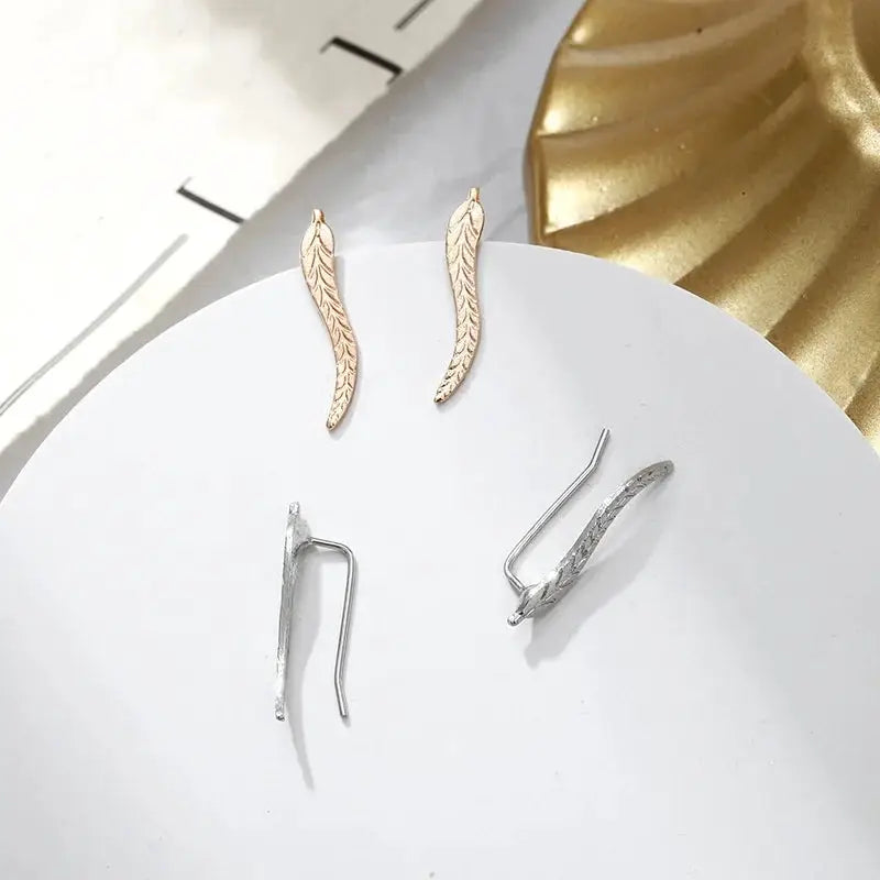 Simples Market gold leaf feather earrings pair, gold-tone with detailed vein pattern; silver earring backs shown