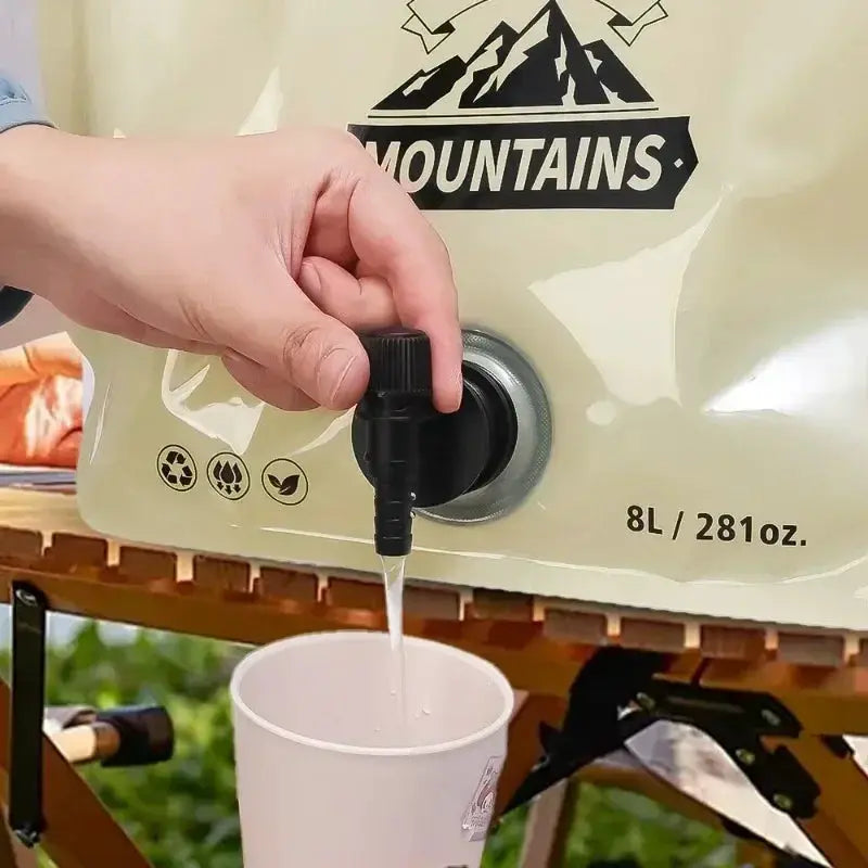 Collapsible water container with spigot, beige bag displaying Mountains logo, 8L capacity.