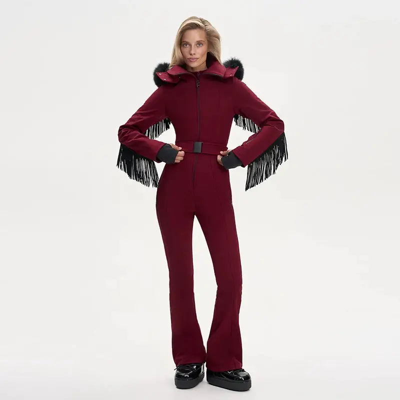 Women's burgundy Simples Market one-piece ski suit with faux fur hood and black fringe tassels on sleeves, waist belt.