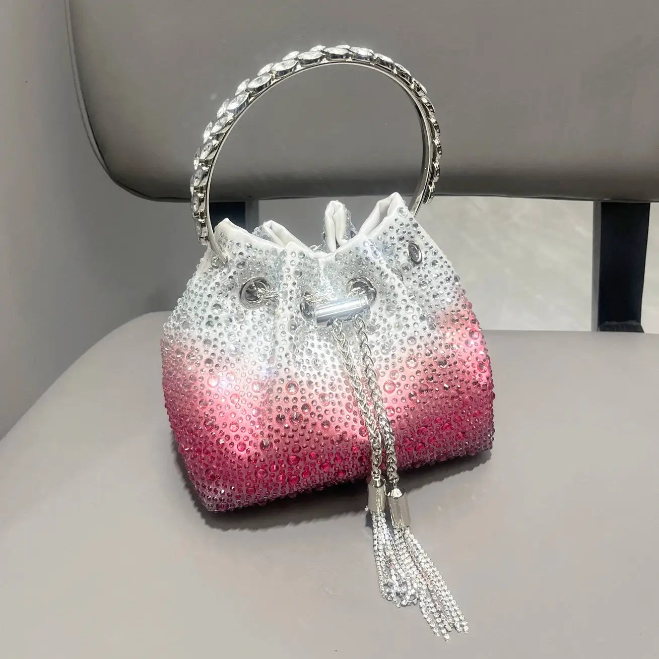 Rhinestone evening clutch bag by Simples Market, white-to-pink gradient with circular crystal handle and silver tassel.