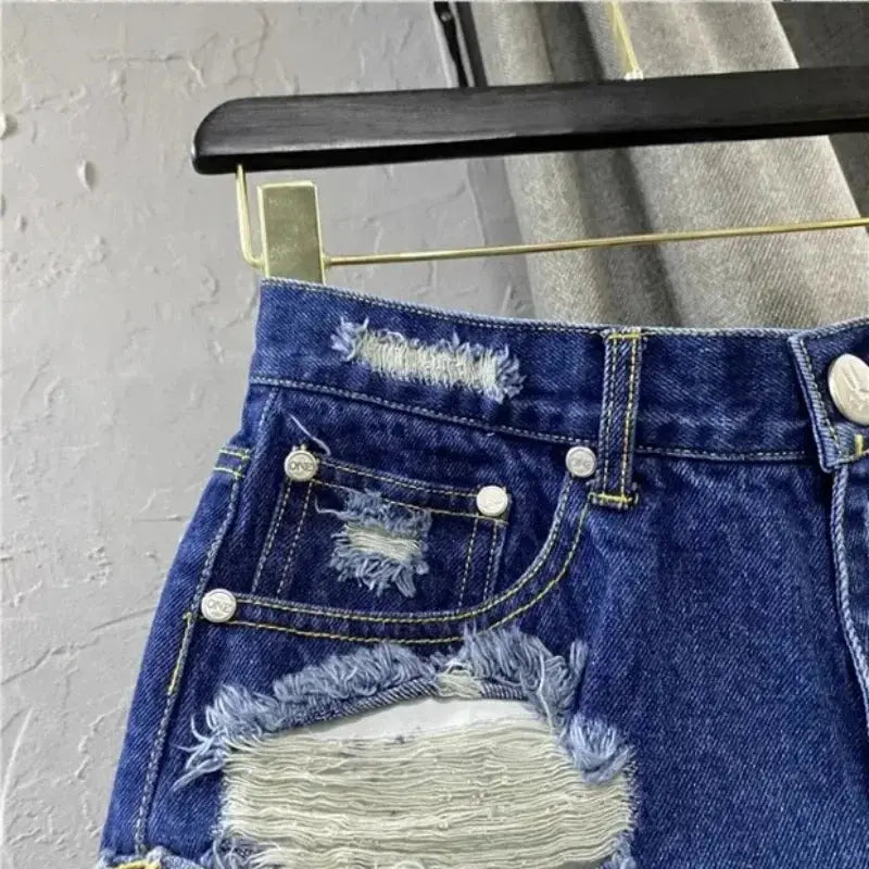 Women's blue denim shorts with distressed frayed edges and ripped patches