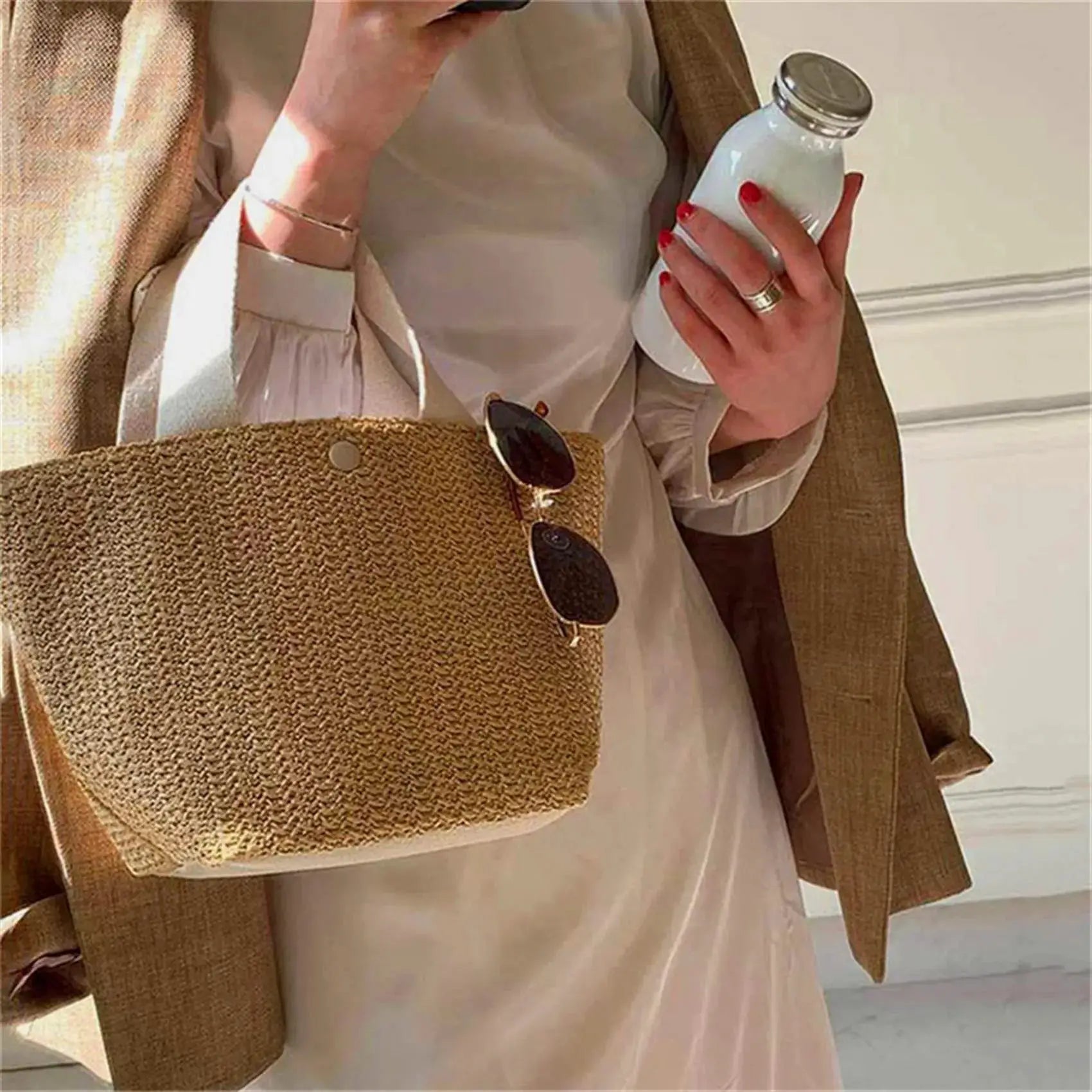 Straw woven handbag tote in natural beige with sunglasses hanging on it