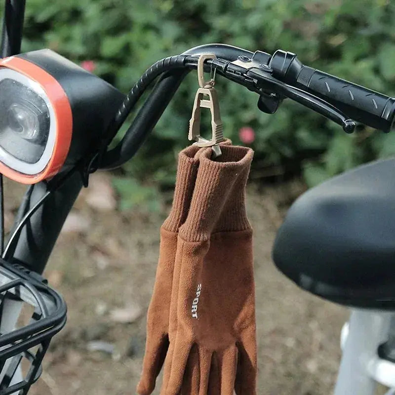 Outdoor protective gloves clip hanger holding brown work gloves on a bike handlebar