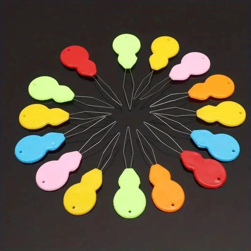 Plastic needle threaders by Simples Market, multicolor set of 16 arranged in a circular layout.
