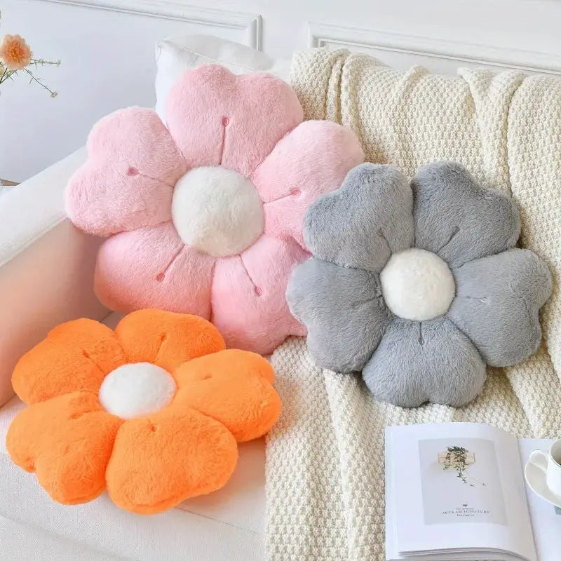 Flower-shaped plush throw pillows, 3-piece set in pink, orange, and gray with white centers, on a sofa.