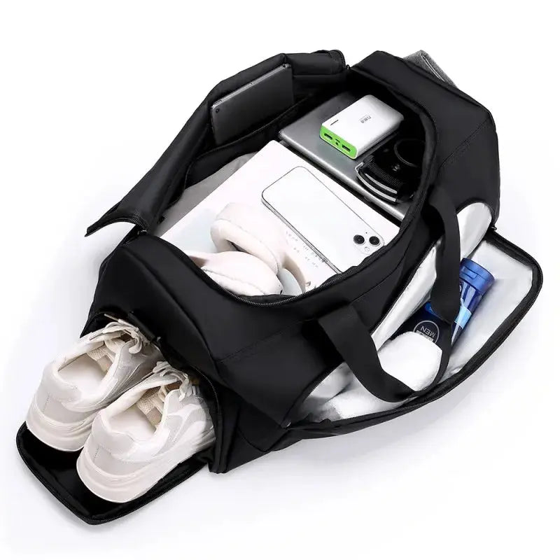 Black sports gym bag with multi-compartment design and shoes storage; holds a pair of white sneakers, clothes and electronics.