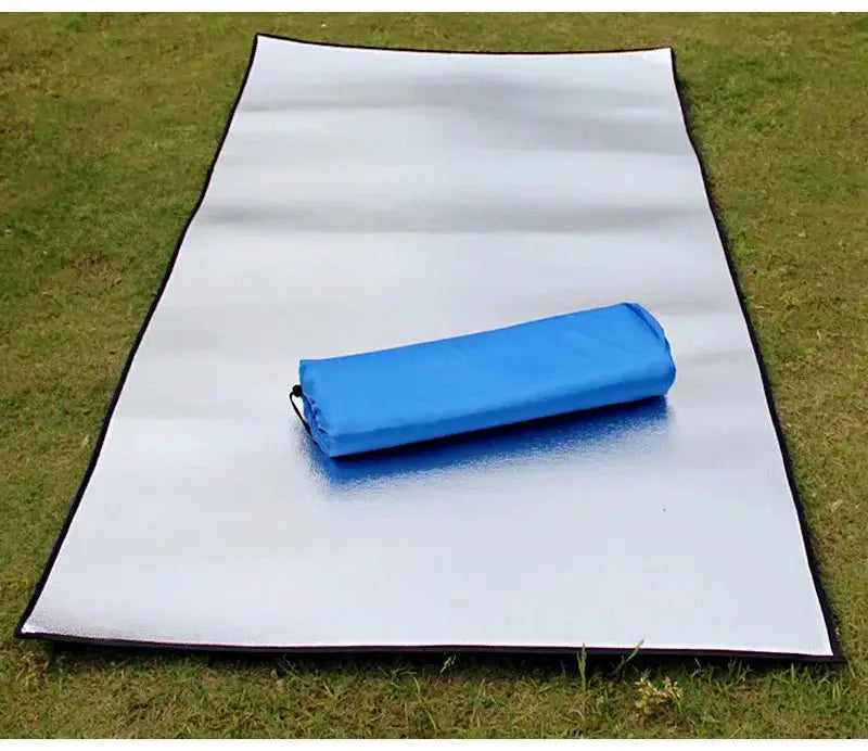 Simples Market camping mat with reflective silver aluminum foil and a blue rolled sleeping pad on grass.