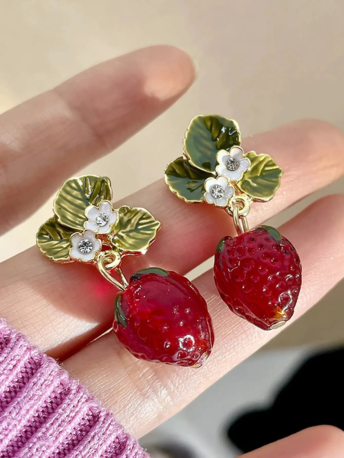 Gold-tone strawberry drop earrings with green leaf motifs, white floral accents and crystal centers