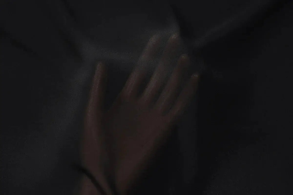 Black see-through chiffon blouse fabric with a hand resting on the sheer material