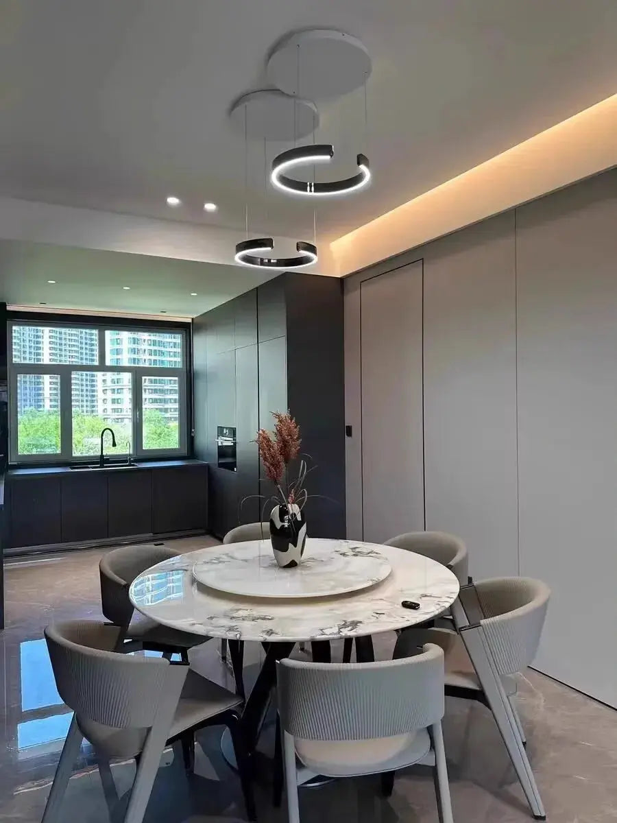 Modern ring ceiling chandelier by Simples Market with LED light rings over round marble dining table