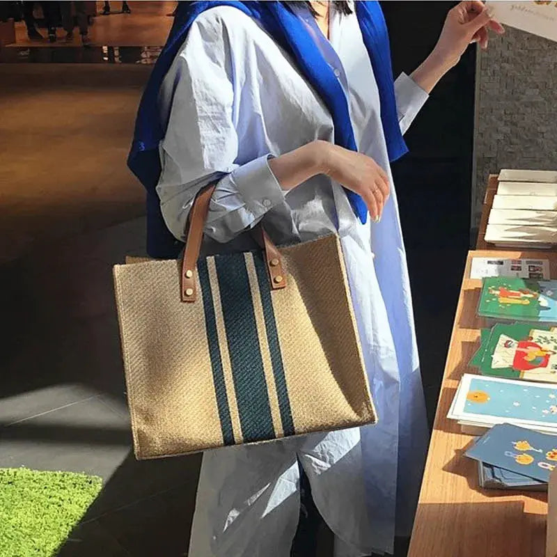 Straw woven tote bag by Simples Market; blue stripe accents, top-handle, large capacity