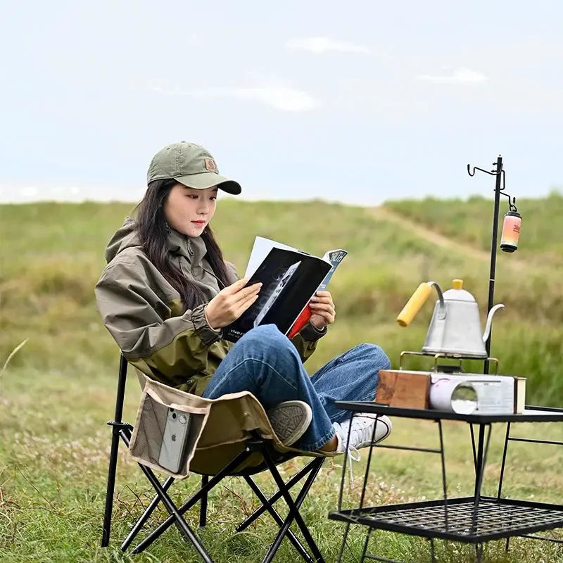 Outdoor folding moon chair with beige canvas seat and black metal frame.