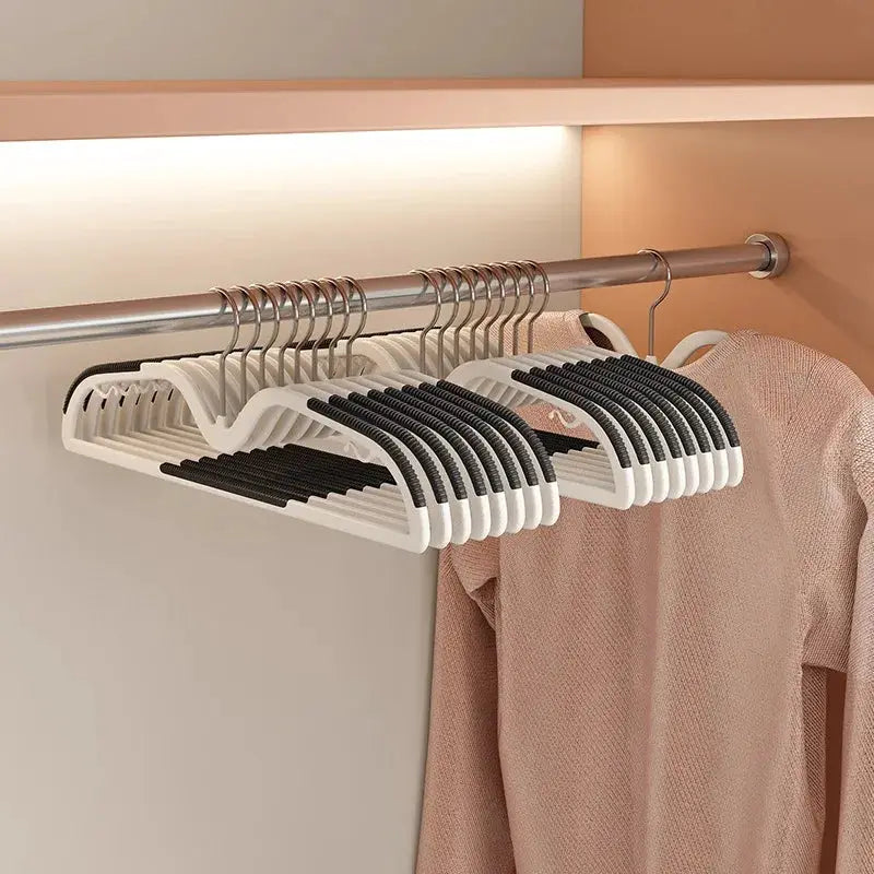 Simples Market short-neck non-slip space-saving clothes hangers, white with black grips on a metal rod beside a pink garment