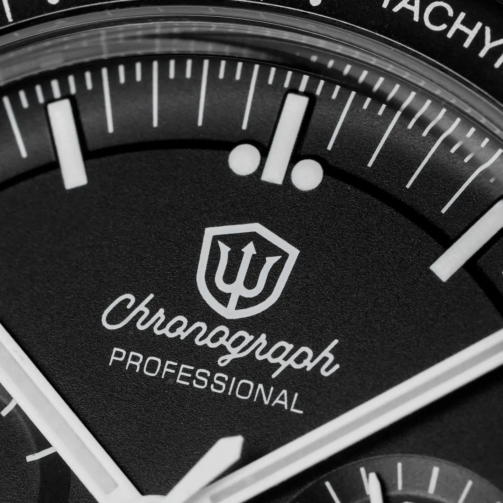 Watch dial close-up: black chronograph face with white markers and shield logo