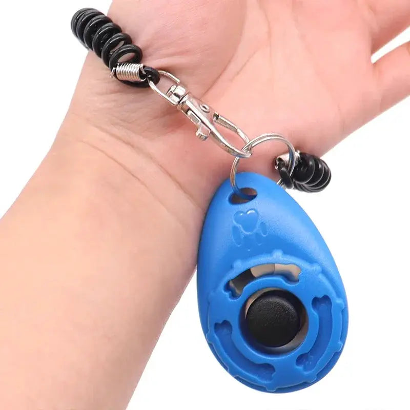 Adjustable dog training clicker by Simples Market with blue teardrop design, wrist strap and keychain.