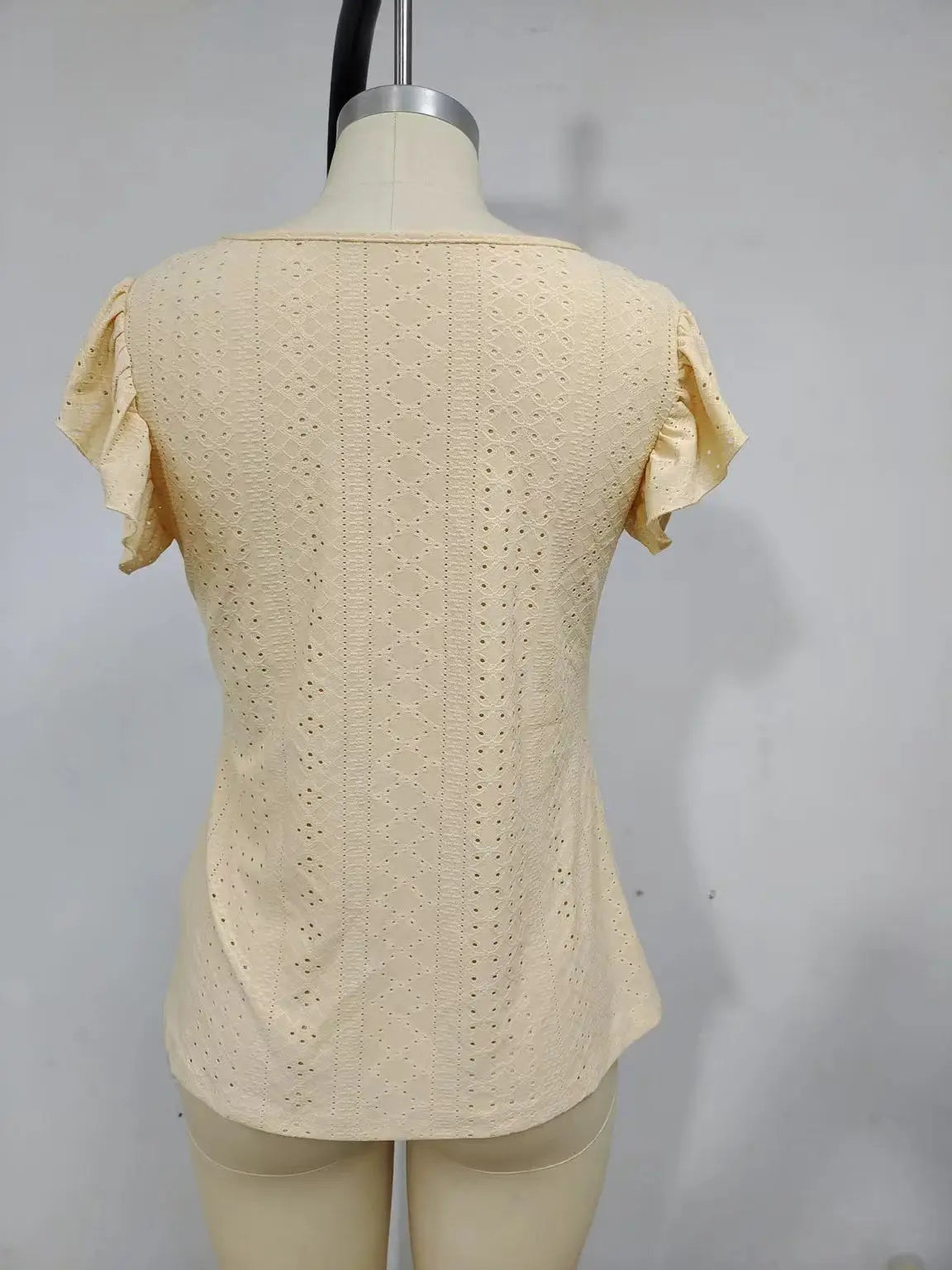 Beige eyelet blouse with short flutter sleeves, lightweight solid color fabric, back view