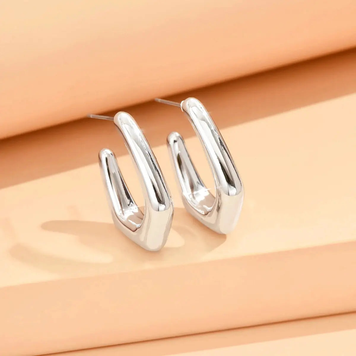 Pair of geometric irregular silver stud earrings with curved chunky shapes, Simples Market