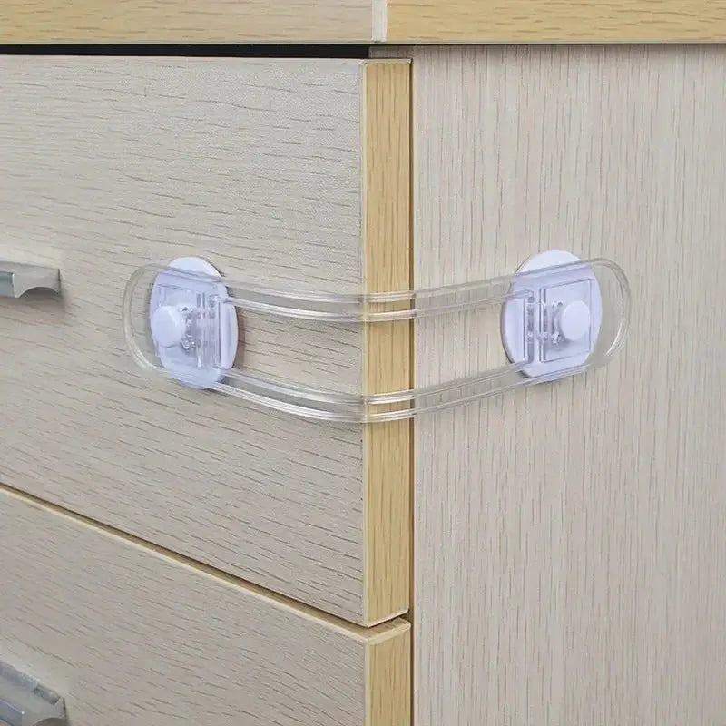 Clear child safety lock with dual straps for drawers and cabinets; transparent straps with white mounts.