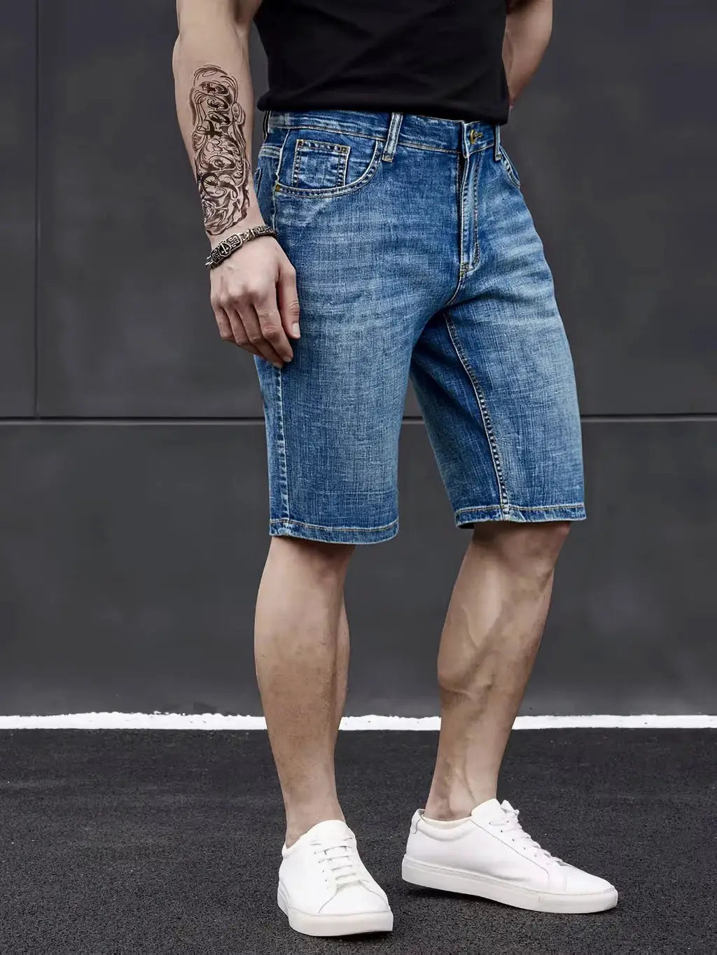 Men's knee-length denim shorts in blue with a straight-stretch fit, paired with white sneakers
