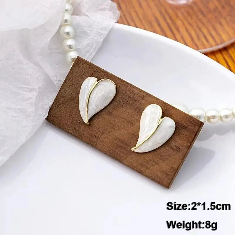 Heart-shaped enamel dangle earrings in white with gold trim, pair