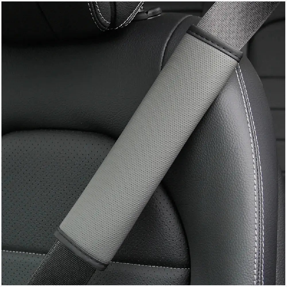Car seat belt shoulder cover in gray perforated fabric for added comfort.