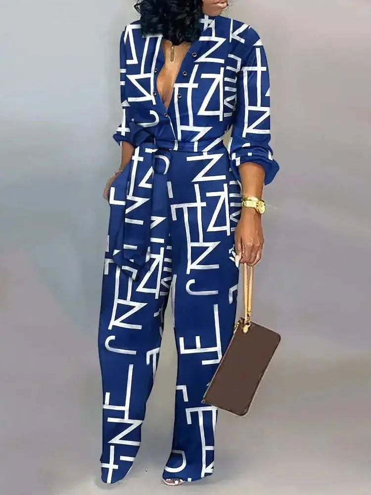 Women's letter-print jumpsuit by Simples Market, blue with white geometric letters, long sleeves, belted waist.