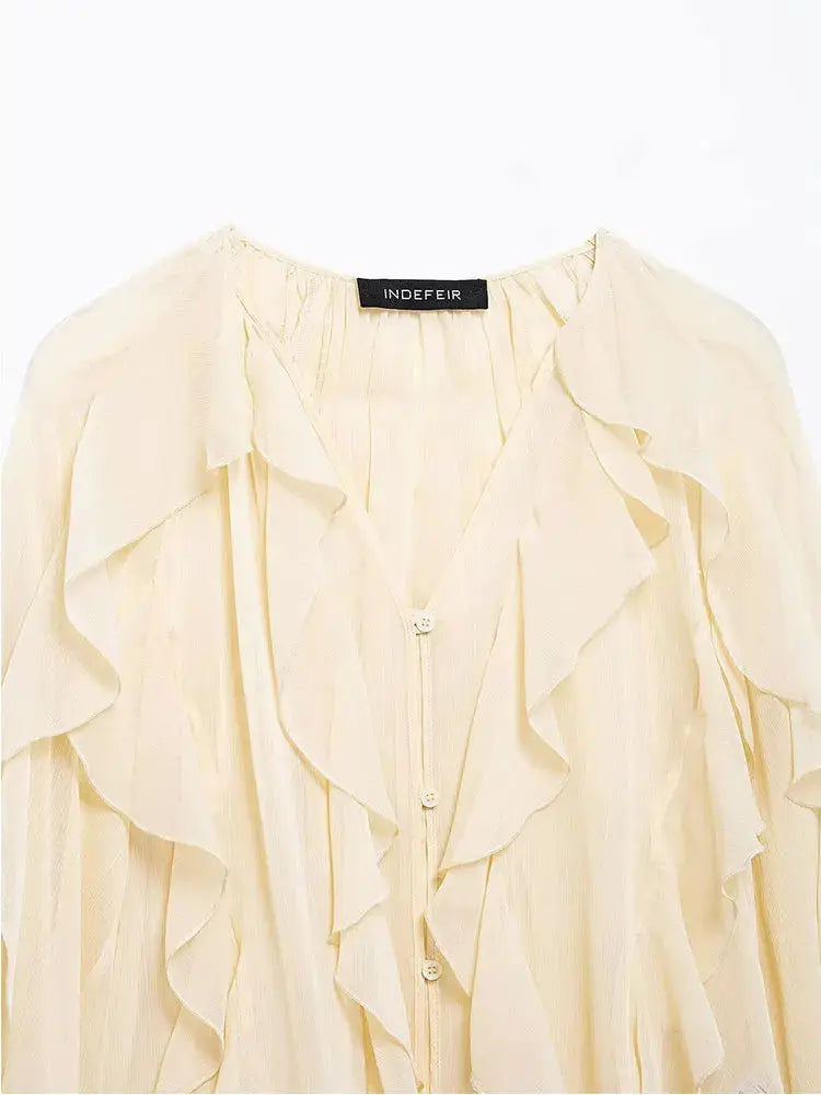 Cream women's blouse with cascading ruffles along front and button-down placket