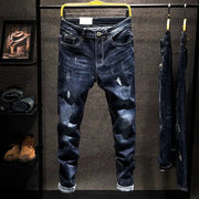 Men's distressed straight jeans in dark blue cotton denim with ripped patches.