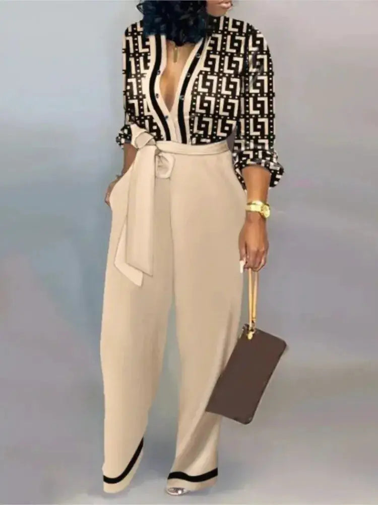 Simples Market women's cream jumpsuit with black geometric print and waist belt, holding a brown handbag