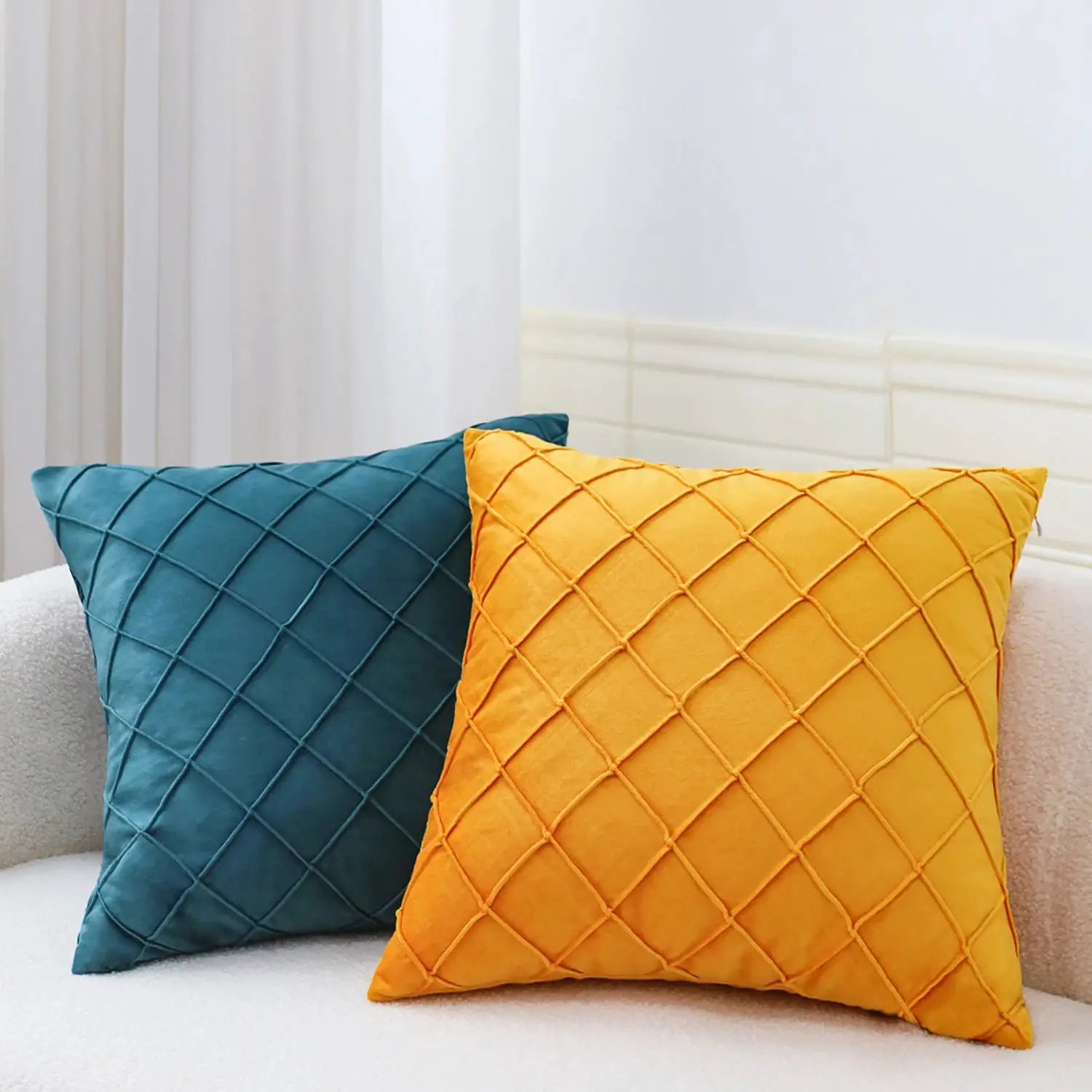 Geometric velvet cushion covers; teal and mustard quilted cushions on a white sofa, two shown.