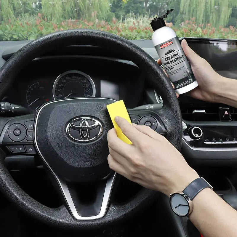 Ceramic Trim Restorer Gel bottle for car interior plastics being applied with a yellow sponge on the steering wheel area
