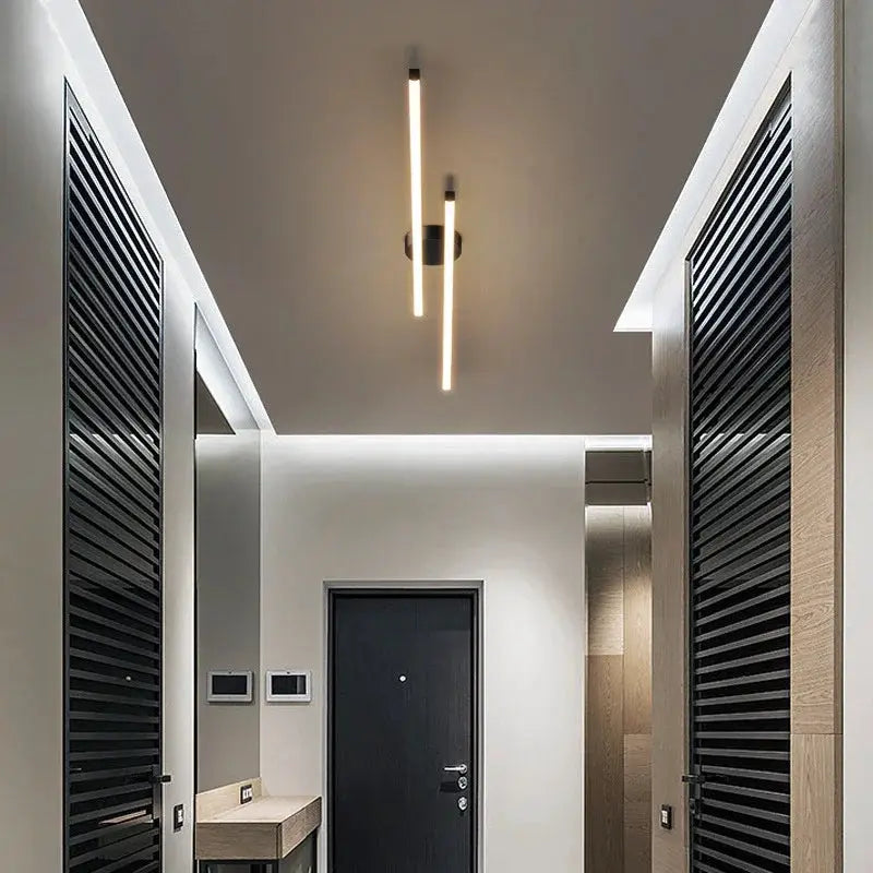 Modern LED ceiling light with two vertical bars emitting warm white light in a hallway