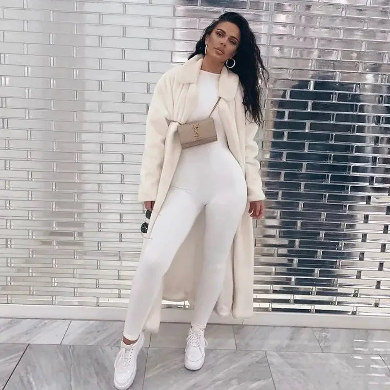 White jumpsuit outfit with cream coat, white sneakers, and beige YSL handbag