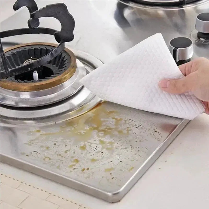 Kitchen disposable non-woven cleaning cloths; white textured cloth wiping oil-stained stainless steel stove
