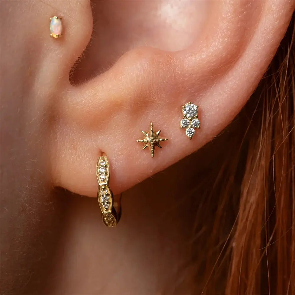 Five-piece earring set featuring gold-tone pavé bar hoop, star stud, diamond cluster studs, and opal helix stud