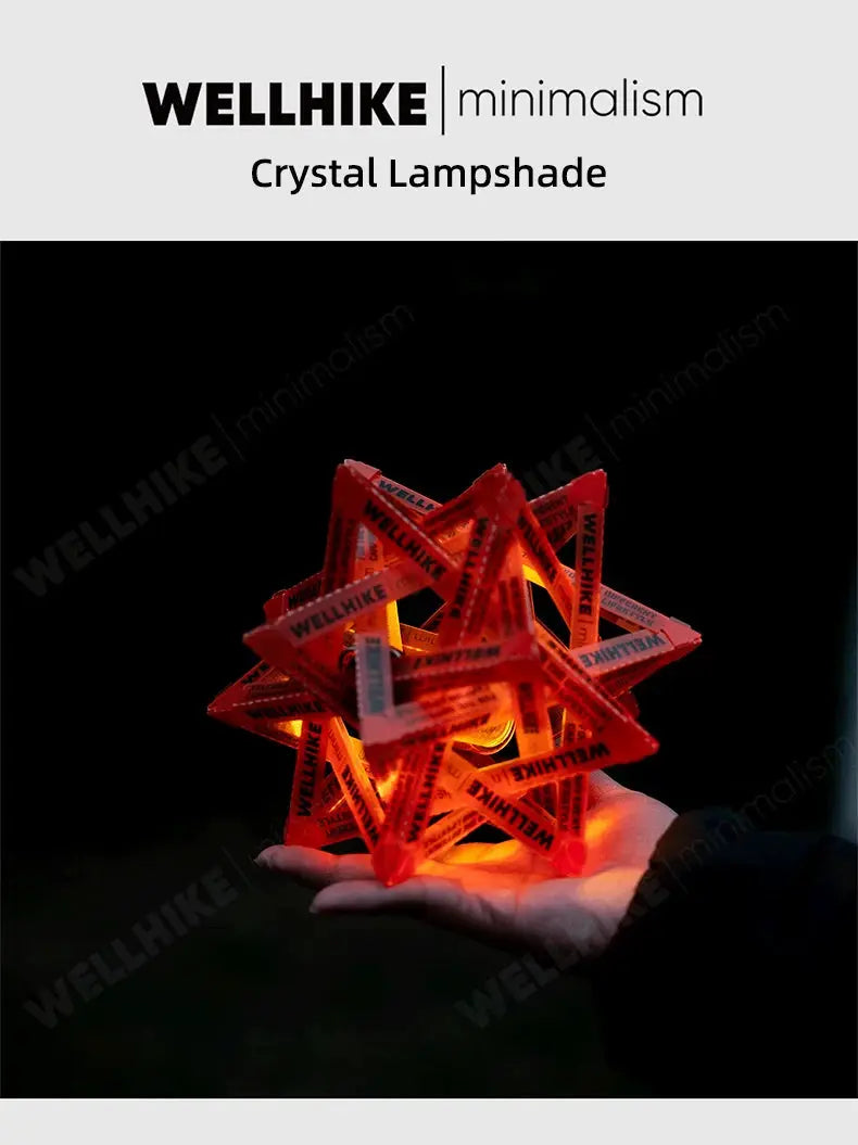 WELLHIKE red star camping lantern shade, illuminated with warm orange glow, held in hand