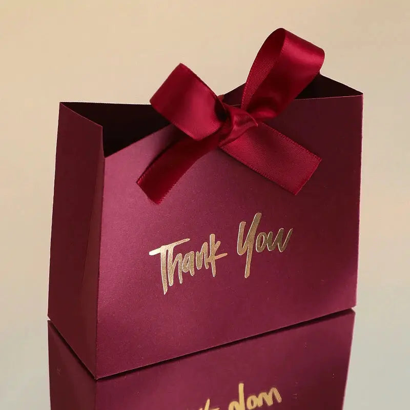 Two burgundy mini gift boxes with gold foil Thank You text and red satin ribbon bow