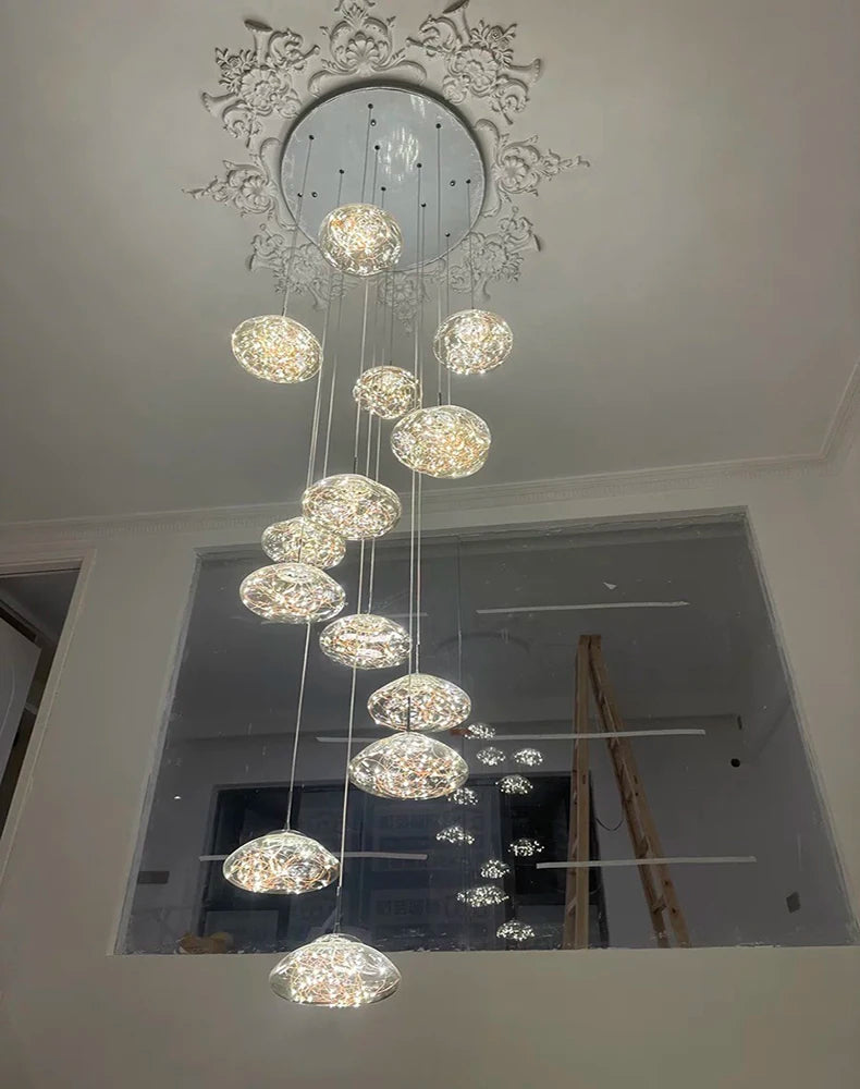 Modern dining room pendant light fixture with cascading crystal orb spheres beneath a decorative ceiling medallion.