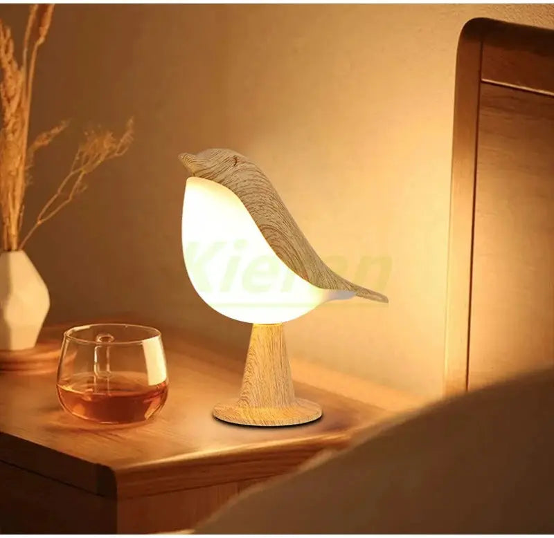 Nordic magpie LED desk lamp on wood base, bird-shaped white shade with wood grain, warm glow.