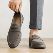 Pair of men's grey suede slip-on loafers with strap detailing, lightweight breathable design and non-slip soft sole.