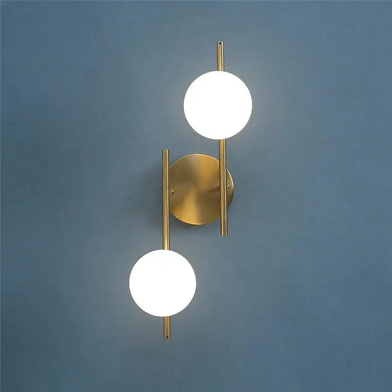 Modern LED wall lamps in brass finish with two milky glass round globes and dual G9 bulbs, bedside-friendly design.