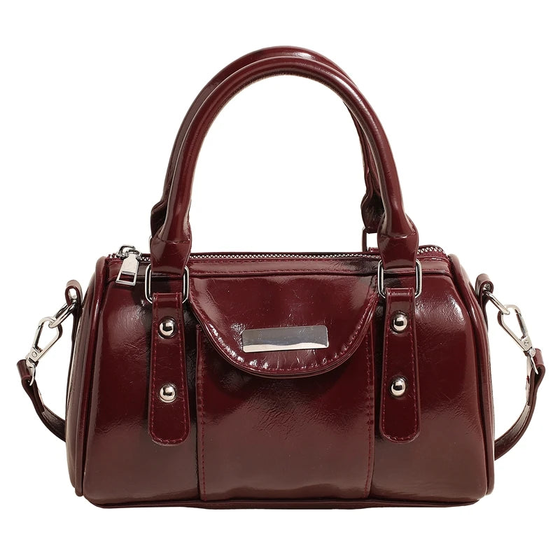Burgundy mini top-handle bag in glossy PU leather with silver hardware and a detachable shoulder strap.