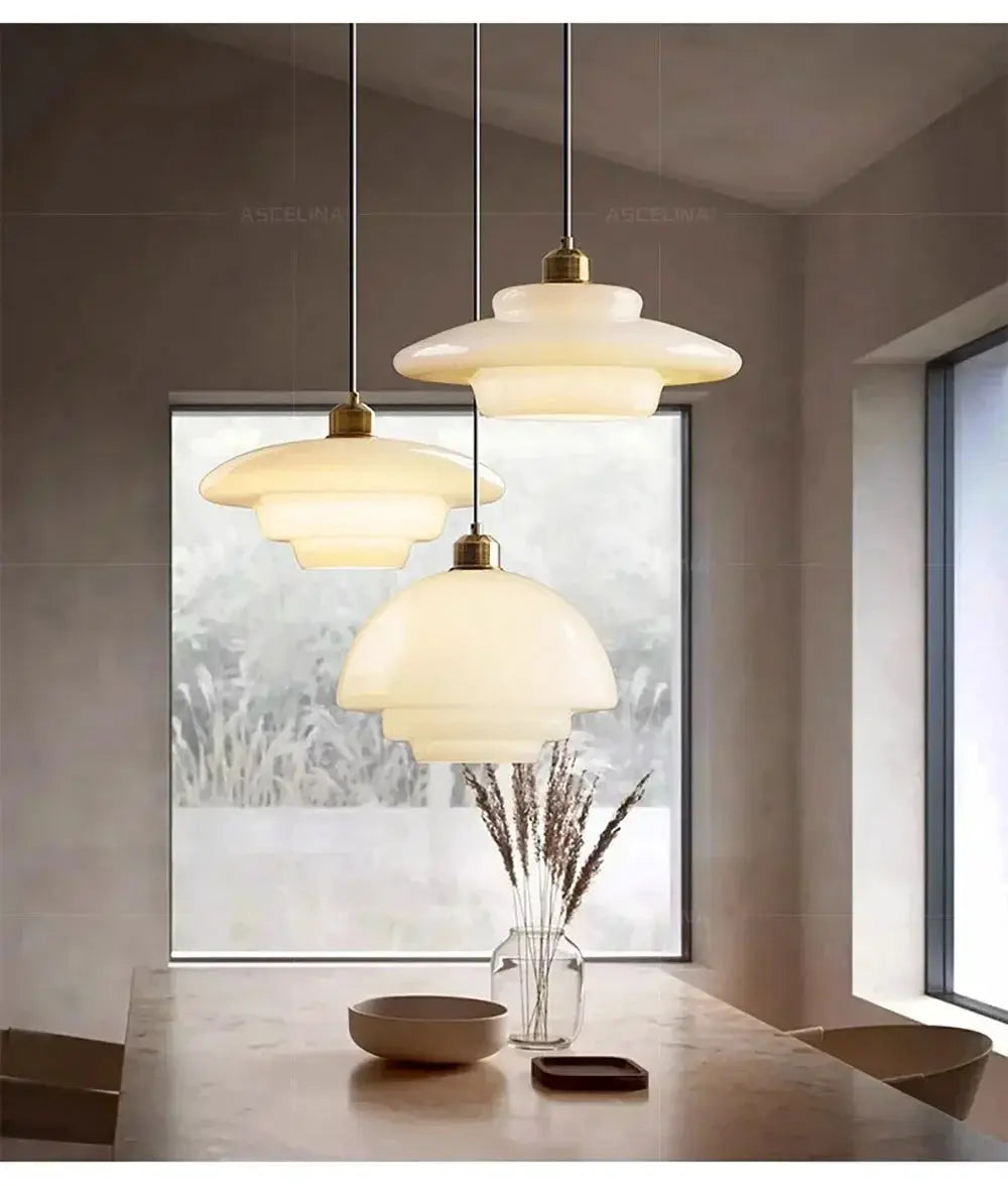 Nordic glass pendant lamps by Simples Market, set of 3 cream glass shades with brass fittings over a kitchen island.