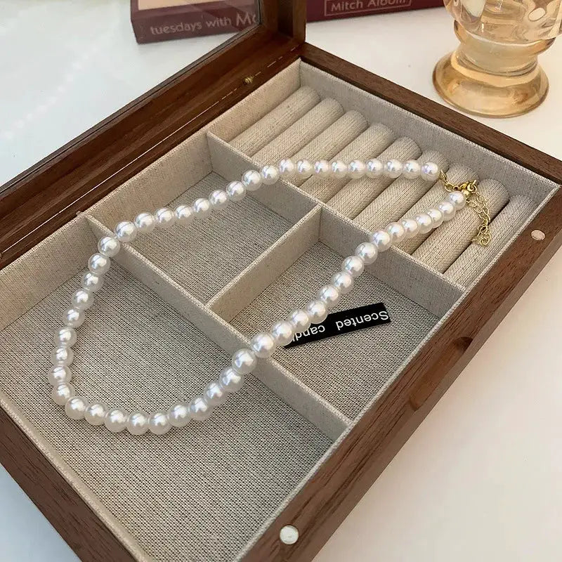 Imitation pearl necklace by Simples Market, white faux pearls on a collarbone chain in a wooden jewelry box