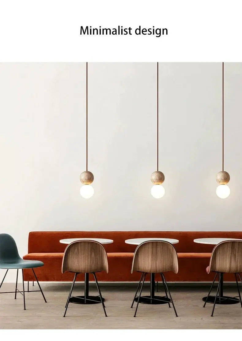 Led pendant lights with stone-cream beads, three hanging fixtures with round bulbs over a dining bench and wooden chairs.