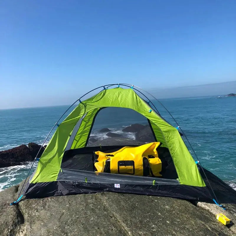 40L-120L Waterproof Duffle by Simples Market; bright yellow bag inside a green camping tent on rocky coast